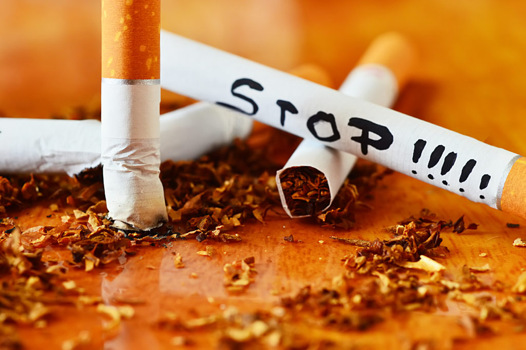 cigarette, tobacco and stop message isolated on wood background close up shot
