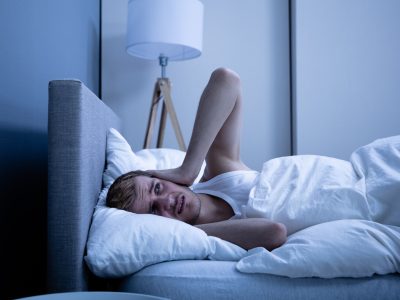 Man Covering His Head With Pillow In Bed